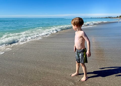 A young boy at the shoreline of a clear turquoise beach